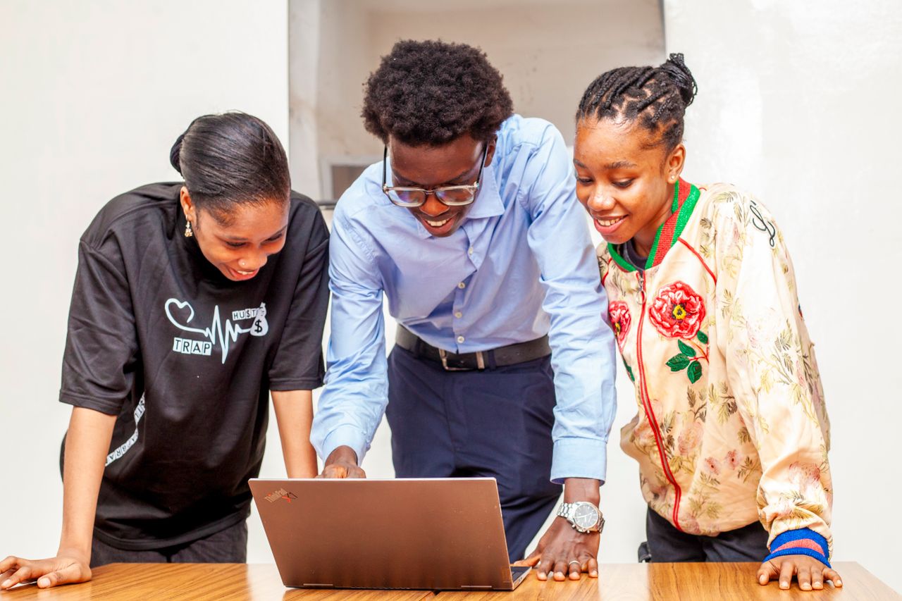 services-06 Three young adults collaborating on a laptop for a digital project indoors.